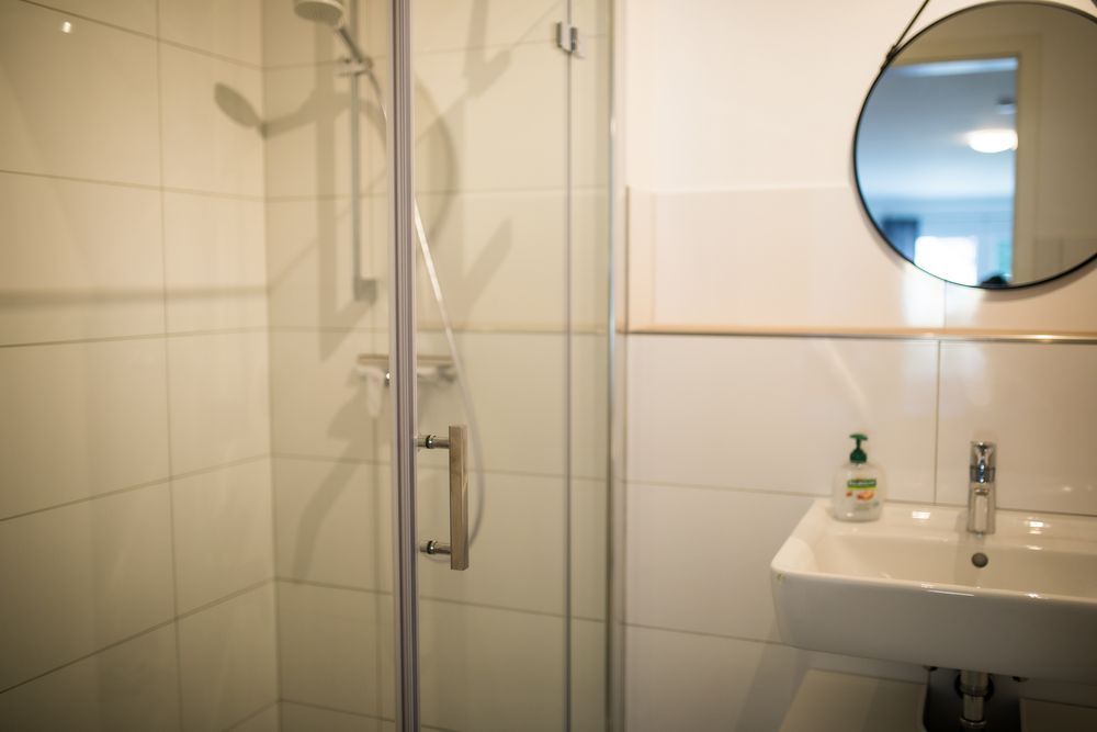 Bad mit Dusche und rundem Spiegel