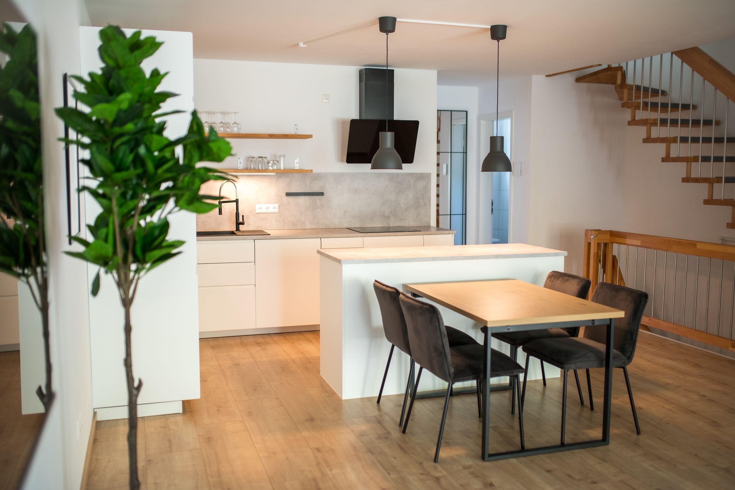 Design Apartment in Bensheim: offene Küche mit Kochinsel, Esstisch und Holztreppe