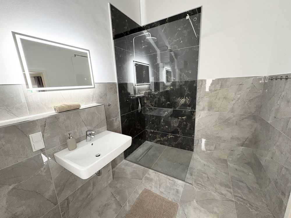 Bad mit bodengleicher Dusche und Marmorwand