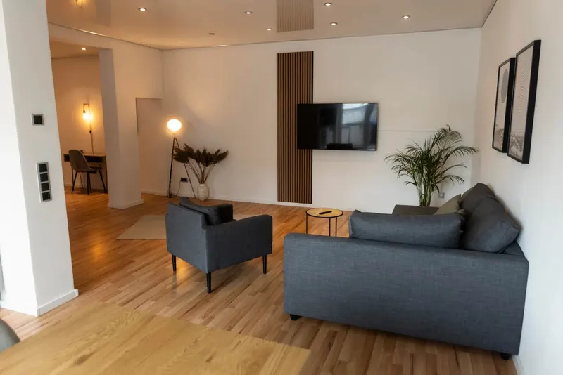 Wohnzimmer mit Ecksofa, Sessel und Smart-TV