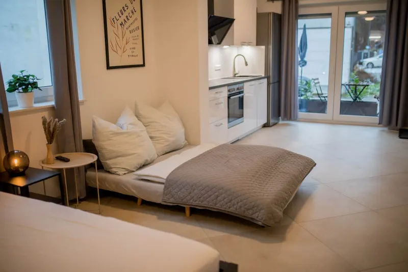 Studio: ausgezogenes Schlafsofa, dahinter Küchenzeile und Terrassentür