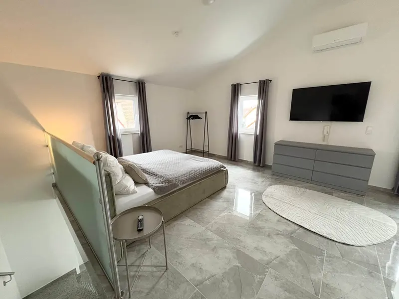 Schlafraum mit Kingsize-Bett, Kommode und Smart-TV