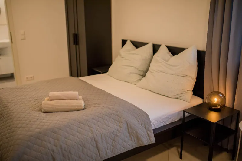 Doppelbett mit Handtüchern und Nachttischlampe