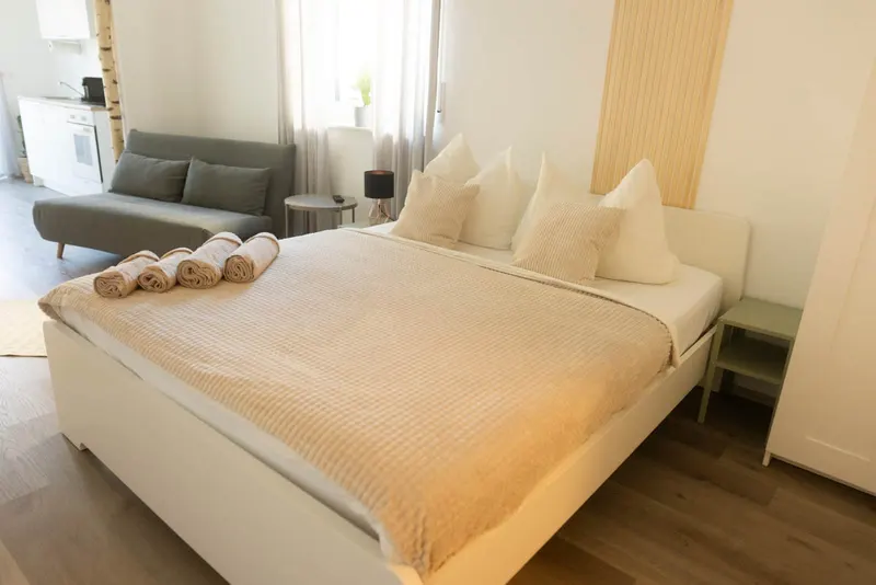 Doppelbett mit Handtüchern, dahinter das Schlafsofa